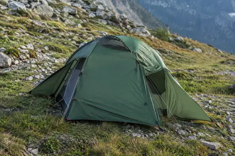 Tente de randonnée verte une place montée sur un sol minéral, avec ses deux vestibules latéraux.