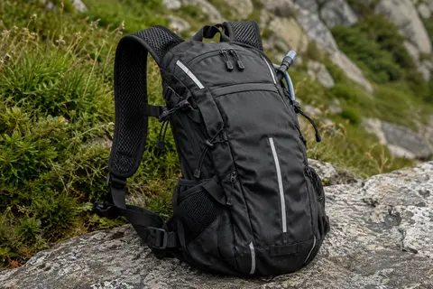 Sac d’hydratation noir compact avec bretelles réglables et bandes réfléchissantes posé sur une pierre